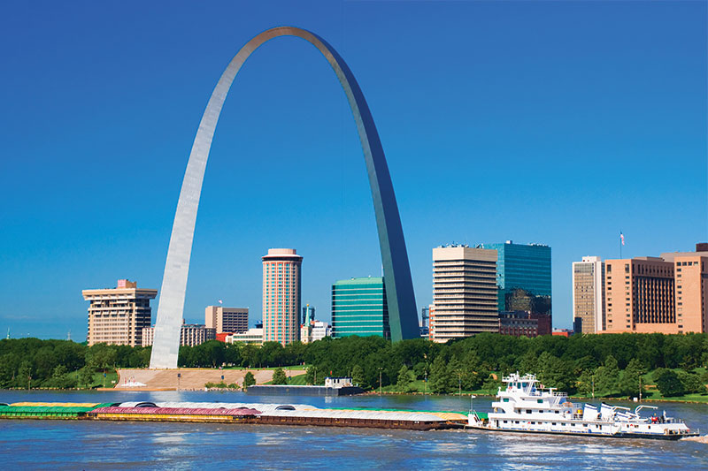 A view of Downtown St Louis and the Gateway Arch with a barge in the foreground.