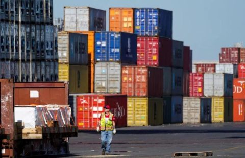A worker walks by stacks of shipping containers at the Port of Philadelphia, Thursday, Oct. 28, 2021.