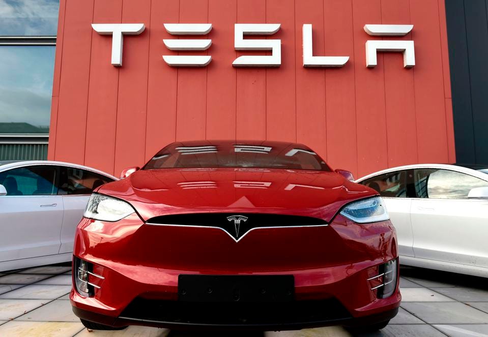 Photo of Tesla automobiles in front of a Tesla branded building